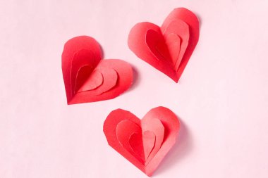 Pembe bir arka plan üzerinde kırmızı kağıt kalpler