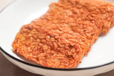 Soya fasulyesinden yapılmış kızarmış Tempeh parçaları bir tabakta servis edilir..