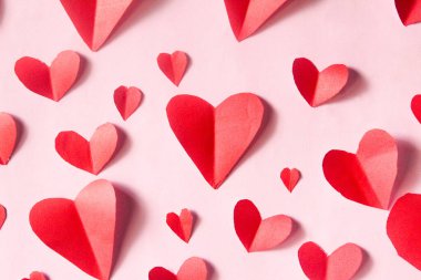 Pembe bir arka plan üzerinde kırmızı kalpler şekli
