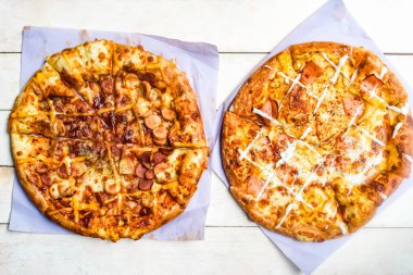 Tahta bir masada iki çeşit pizza.