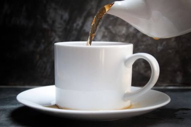 Çaydanlıktan bir fincana çay dolduruyorum.