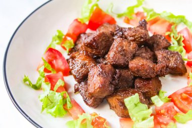 Bir tabak doğranmış biftek ve salata.