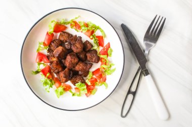 Bir tabak doğranmış biftek ve salata.