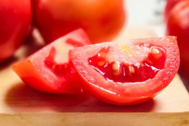 Tahta bir masanın üzerinde dilimlenmiş kırmızı domateslerin yakın çekimi.