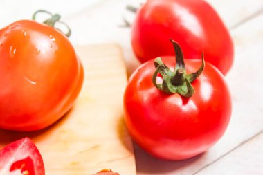 Kesme tahtasındaki birkaç kırmızı domatesin yakın çekimi.