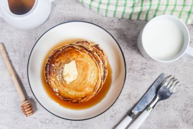 Kahvaltı menüsü olarak masaya bal, tereyağı ve bir fincan süt konulmuş bir gözleme.