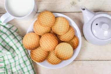 Kahvaltı menüsü olarak bisküvi ve süt, ahşap bir masada.