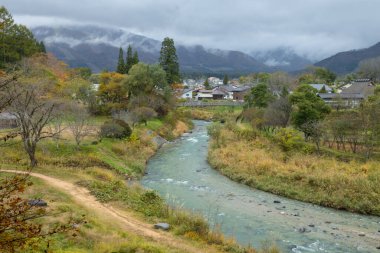 Beautiful view of Hakuba Village with the Japan Alps as a backdrop and a clear stream flowing through it in autumn, view from Oide Park, Nagano Prefecture, Japan  clipart