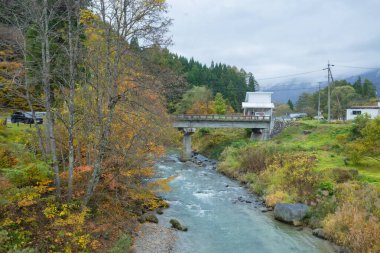 Japon Alpleri 'nin arka planda olduğu Hakuba Köyü' nün güzel manzarası ve sonbaharda içinden akan temiz bir dere, Oide Park, Nagano Bölgesi, Japonya manzarası 