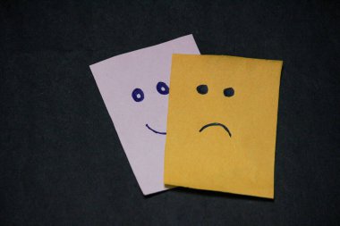 Siyah arka planda üzgün yüzlü kağıt.