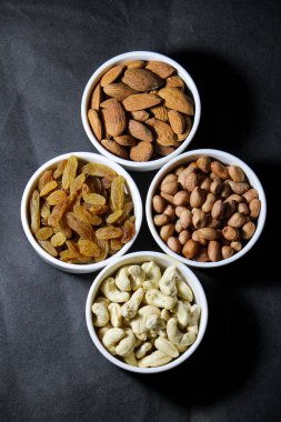 Gri beton bir masa üzerinde fındık, kuru üzüm ve badem seti.