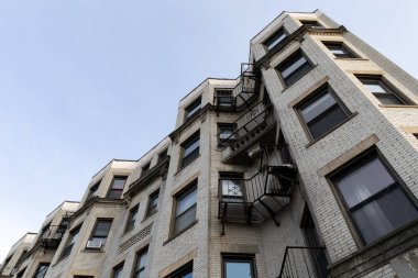 Hafif tuğlalı bir apartmanın dalgalı yüzeyi. Aşırı yüksek bir açıdan görünüyor. Metal ızgara balkonları, yatay görünüm.