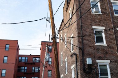 Elektrik direkleriyle ve çizgileriyle eski kentsel tuğla apartman binalarının arka manzarası, yatay görünüm