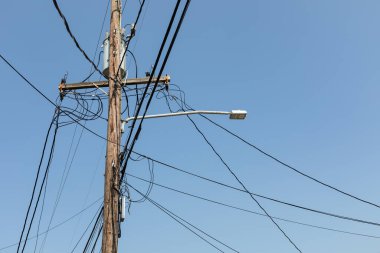 Halatları ve kabloları olan elektrik direği, mavi gökyüzüne bağlı sokak lambası ve trafo, yaratıcı kopya alanı, yatay görünüm