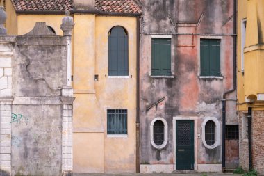 Venedik 'in renkleri. Alçı duvarlı arka plan ve kapalı panjurlu pencereler. Venedik sarısı, deniz mavisi ve tozlu pembe. Renklerin uyumlu kombinasyonu.