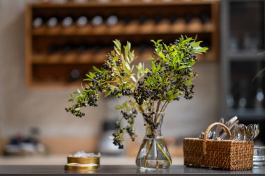 Cam vazoda böğürtlenli bir dal. İçinde yabanmersini dalı olan bir vazo. Bokeh arkaplanı.