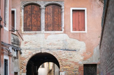 Street with archway in the historical italian town, Venice. Close-up of windows in historical house with brown blinds closed. clipart