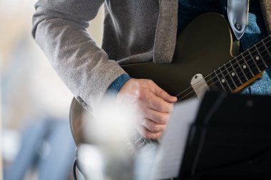 Arka plan için sahnede gitarist, yumuşak ve bulanık bir konsept. Gitar çalarak elinizi kapatın. Gitar çalan müzisyen, canlı müzik arka planında. Orkestra sahnede, caz müzik konserinde.