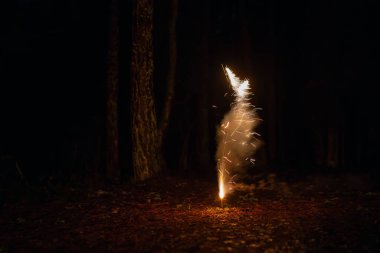 Gece vakti yerde havai fişekler patlaması. Karanlık gece geçmişine sahip havai fişekler. Yeni yıl arifesinde ışıl ışıl yanan havai fişek volkanı.