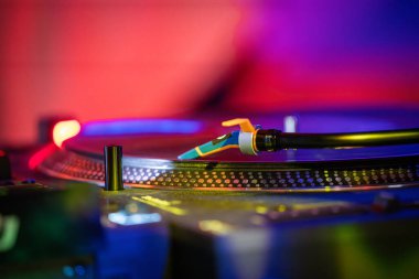 Düşük ışık resimli vinil plak detaylarıyla donatılmış. Pikabın plağı kırmızı ve mavi arka planda. Pikabın yakın çekim detayları kayıtta.