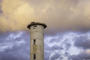 Terk edilmiş balık fabrikasının su kulesi binasının dışı. Renkli günbatımına karşı eski terk edilmiş balık fabrikası su kulesi.