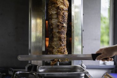 Şef geleneksel Türk donör kebap eti hazırlıyor ve yapıyor. Ev restoranında geleneksel Türk yemeği Doner Kebabı veya Yunan jiroskopu yapmak için ızgara et kullanılır. Dilimleme Doner Kebabı.