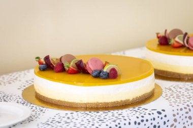 Kutlama için taze meyve ve makronla süslenmiş cheesecake tatlısı. Canlı taze meyveler ve narin bir makronla süslenmiş el yapımı peynirli kekin yakın çekimi. Harika bir mutfak deneyimi..