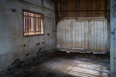Interior of abandoned fish factory with wooden wall. Whitewashed walls in old factory building.