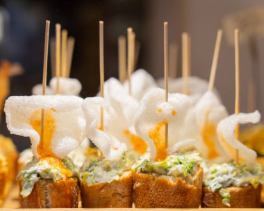 Typical snack of Basque Country, pinchos or pinxtos skewers with small pieces of bread, sea food, eggs, cheese served in bar in Bilbao, Spain.