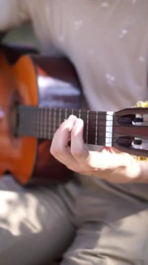 Genç adam dışarıda akustik gitar çalıyor. Yüksek kalite 4k görüntü