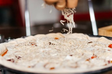 Evde pizza pişirip rendelenmiş peynir yaymak. Yüksek kalite fotoğraf