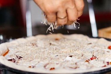 Evde pizza pişirip rendelenmiş peynir yaymak. Yüksek kalite fotoğraf