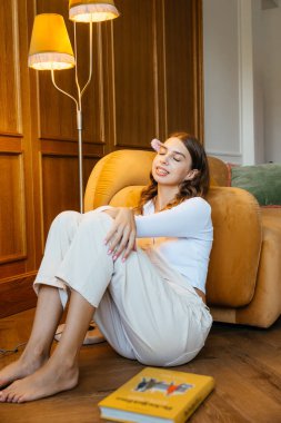 Harika bir atmosferi ve sarı lambası olan rahat bir odada kanepede uzanmış genç bir kız. Yüksek kalite fotoğraf