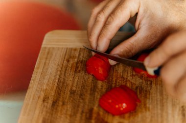 Bir şef domatesi kesme tahtasının üzerinde bıçakla kesiyor. Yüksek kalite fotoğraf