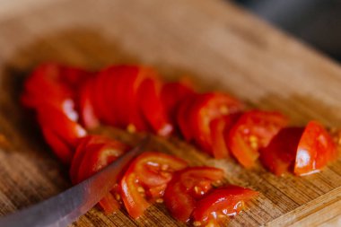 Bir şef domatesi kesme tahtasının üzerinde bıçakla kesiyor. Yüksek kalite fotoğraf