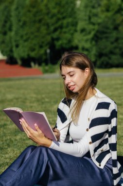 Öğrenci kız yazın dışarıda çalışıyor. Holliday 'de yeşil çimlerin üzerinde dizüstü bilgisayar kullanıyor ve not alıyor.