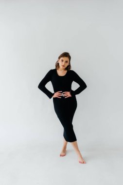 Siyah kurdeleli, kendine güvenen genç bir kadın zarif beyaz bir arka plana karşı zarif bir şekilde poz verir. Zarafeti ve tarzı somutlaştırır. Yüksek kalite fotoğraf