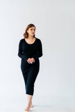 Siyah kurdeleli, kendine güvenen genç bir kadın zarif beyaz bir arka plana karşı zarif bir şekilde poz verir. Zarafeti ve tarzı somutlaştırır. Yüksek kalite fotoğraf