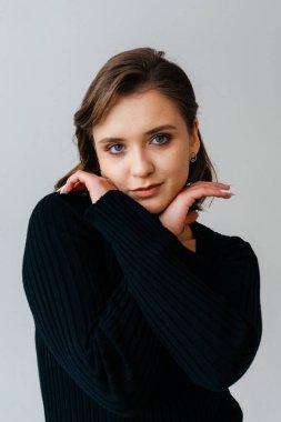 Siyah kurdeleli, kendine güvenen genç bir kadın zarif beyaz bir arka plana karşı zarif bir şekilde poz verir. Zarafeti ve tarzı somutlaştırır. Yüksek kalite fotoğraf