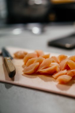 Kesme tahtasındaki taze kesilmiş tavuğun yakın çekimi bıçakla, ev mutfağında yemek hazırlama gösterisi. Yüksek kalite fotoğraf