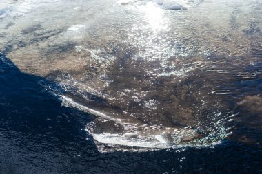 Donmuş buz tabakaları, kışın doğasının güzelliğini ve kırılganlığını tasvir eden karanlık, soğuk bir nehrin yüzeyinde parçalanır. Yüksek kalite fotoğraf