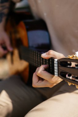 Genç adamlar dışarıda akustik gitar çalıyorlar. Yüksek kalite fotoğraf