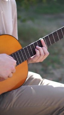 Genç adam dışarıda akustik gitar çalıyor. Yüksek kalite 4k görüntü