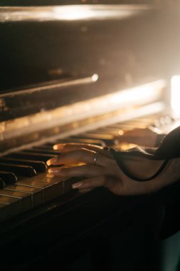 Antika piyano çalan bir kadının estetik yakın çekimi nostalji ve zarafeti çağrıştırıyor. Yüksek kalite fotoğraf
