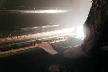 Antika piyano çalan bir kadının estetik yakın çekimi nostalji ve zarafeti çağrıştırıyor. Yüksek kalite fotoğraf