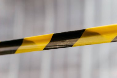 Açık hava sahnesi boyunca uzanan sarı ve siyah bir uyarı bandı tehlike, kısıtlama ve güvenliği sembolize ediyor. Yüksek kalite fotoğraf