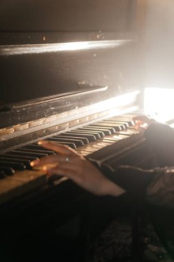 Antika piyano çalan bir kadının estetik yakın çekimi nostalji ve zarafeti çağrıştırıyor. Yüksek kalite fotoğraf