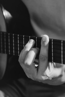Genç adamlar siyah beyaz dışarıda akustik gitar çalıyorlar. Yüksek kalite fotoğraf