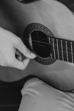 Genç adamlar siyah beyaz dışarıda akustik gitar çalıyorlar. Yüksek kalite fotoğraf