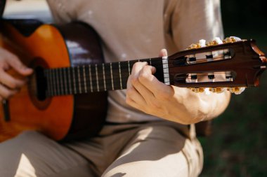 Genç adamlar dışarıda akustik gitar çalıyorlar. Yüksek kalite fotoğraf